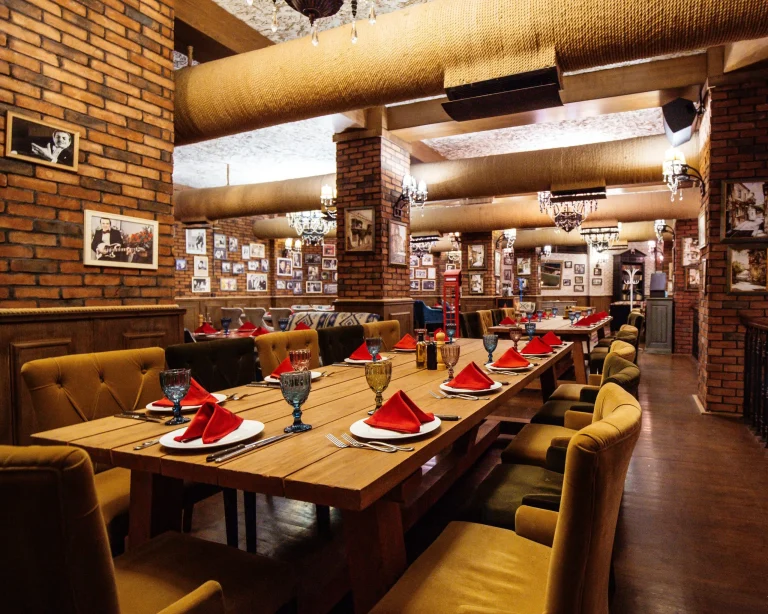 restaurant-hall-with-red-brick-walls-wooden-tables-pipes-ceiling-scaled